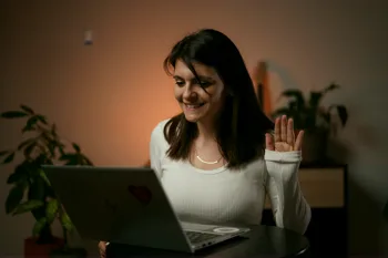 Marija Jovanović ispred laptopa, maše kameri tokom Zoom časa, toplo večernje svetlo