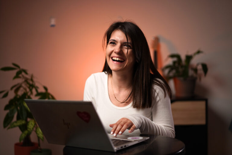 Marija Jovanović za radnim stolom, smeje se ispred laptopa